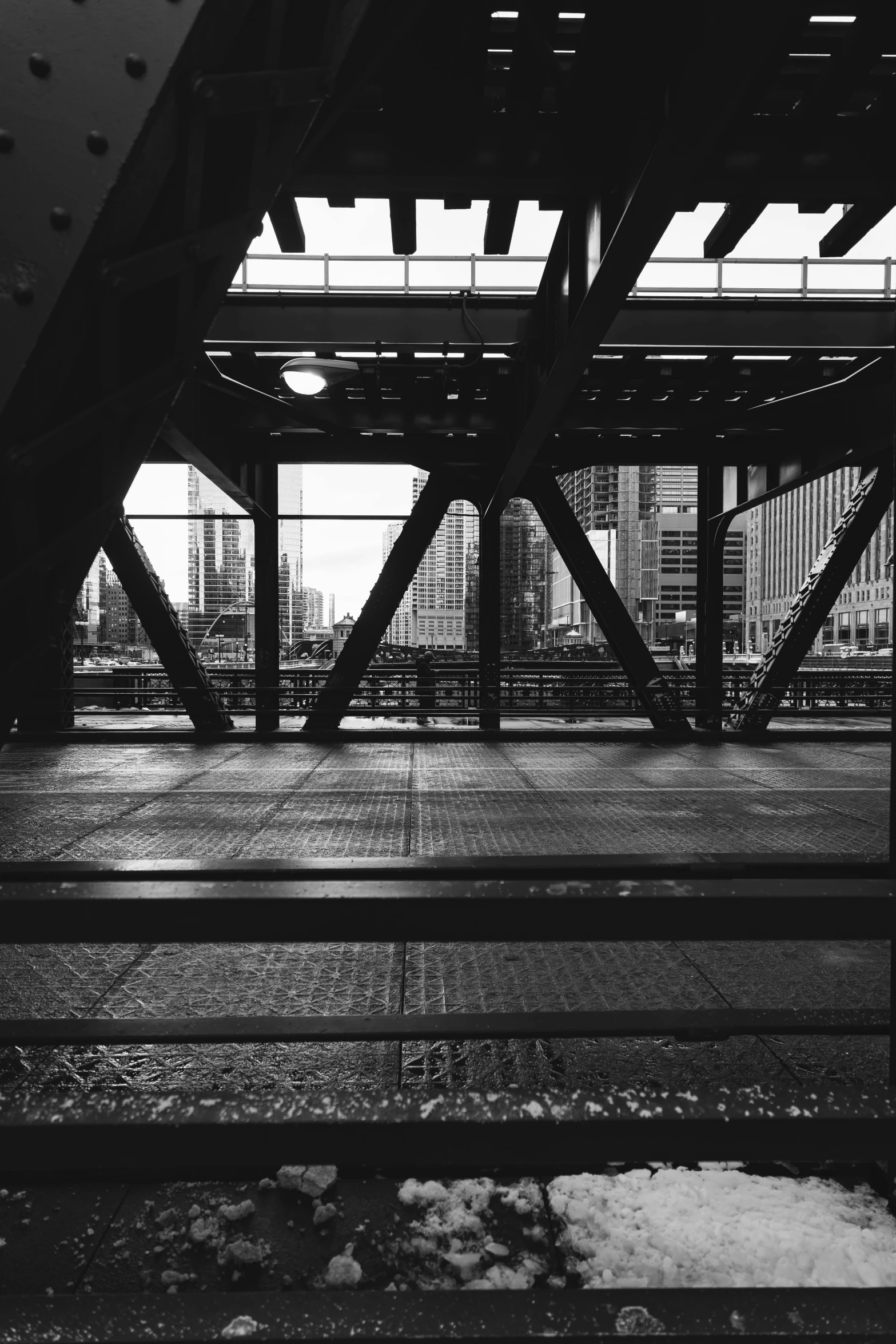 a black and white photo of a train station, inspired by Thomas Struth, happening, on a bridge, location [ chicago ( alley ) ], looking out, metal scapes