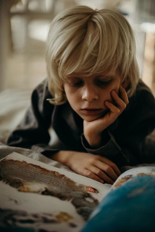 a little boy laying on a bed reading a book, pexels contest winner, looking off to the side, a blond, thumbnail, student