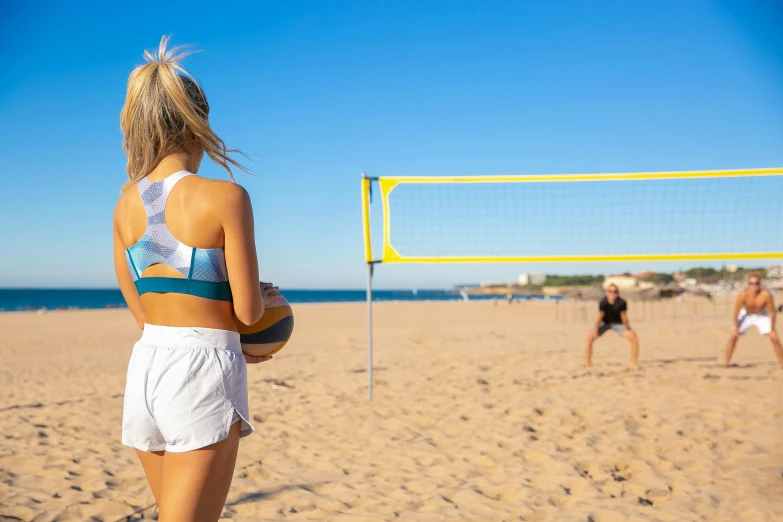 a woman standing on a beach holding a volleyball ball, arabesque, sport bra and dark blue shorts, panels, australian beach, on a yellow canva