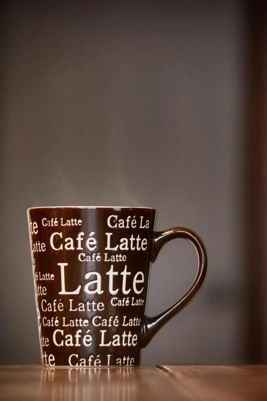 a coffee cup sitting on top of a wooden table, sitting on a mocha-colored table, language, lattice, it's late at night