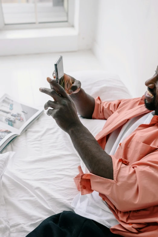 a man sitting on a bed using a cell phone