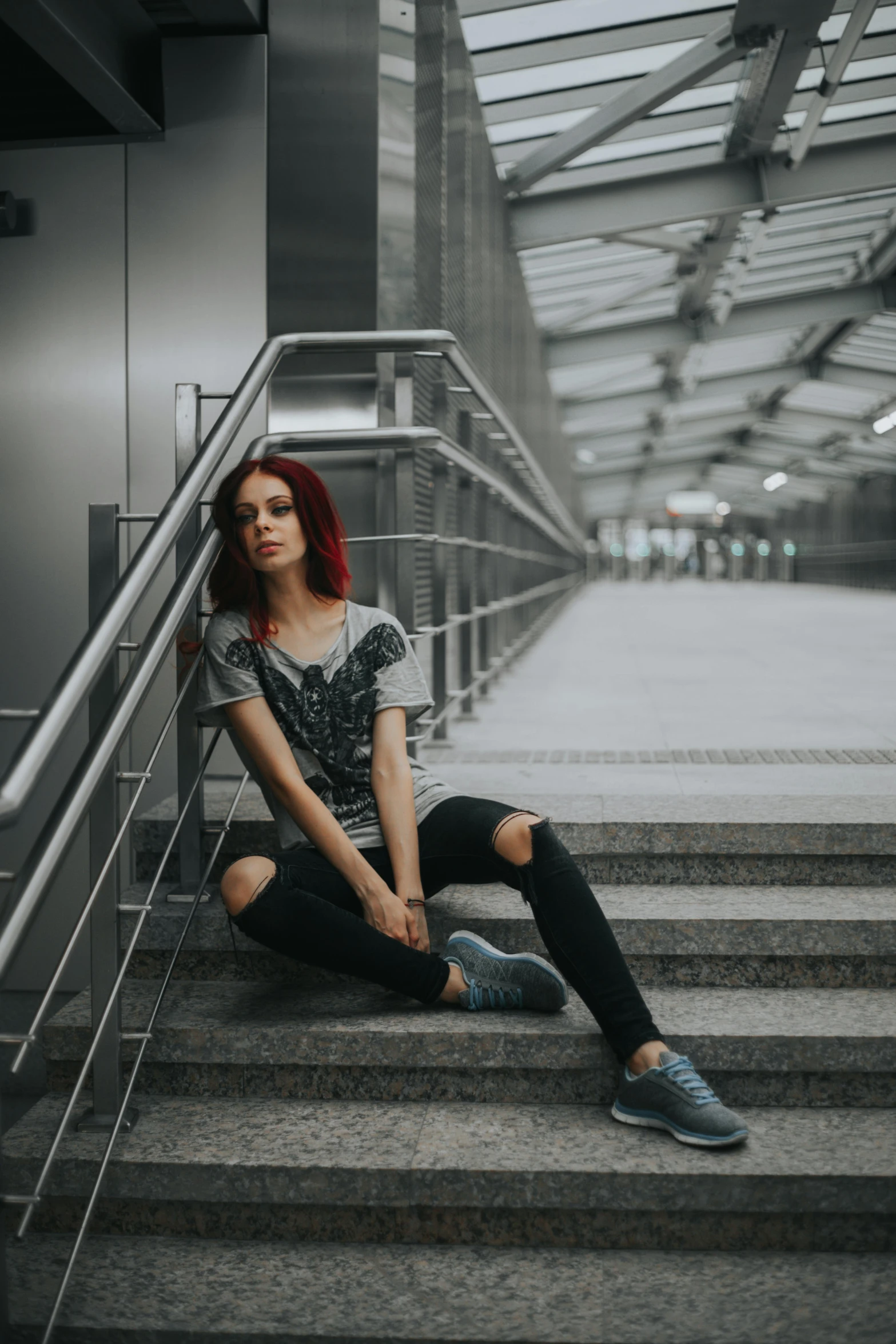 a woman sitting on a set of stairs, inspired by Elsa Bleda, pexels contest winner, graffiti, redhead girl, gray shirt, mall goth, casual pose