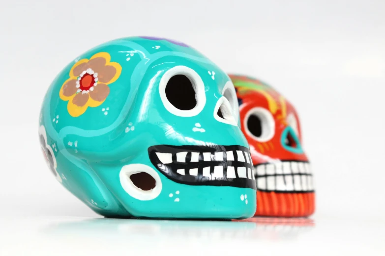 a couple of skulls sitting next to each other, by Juan O'Gorman, pexels contest winner, folk art, orange and teal, headshot, made of glazed, slide show