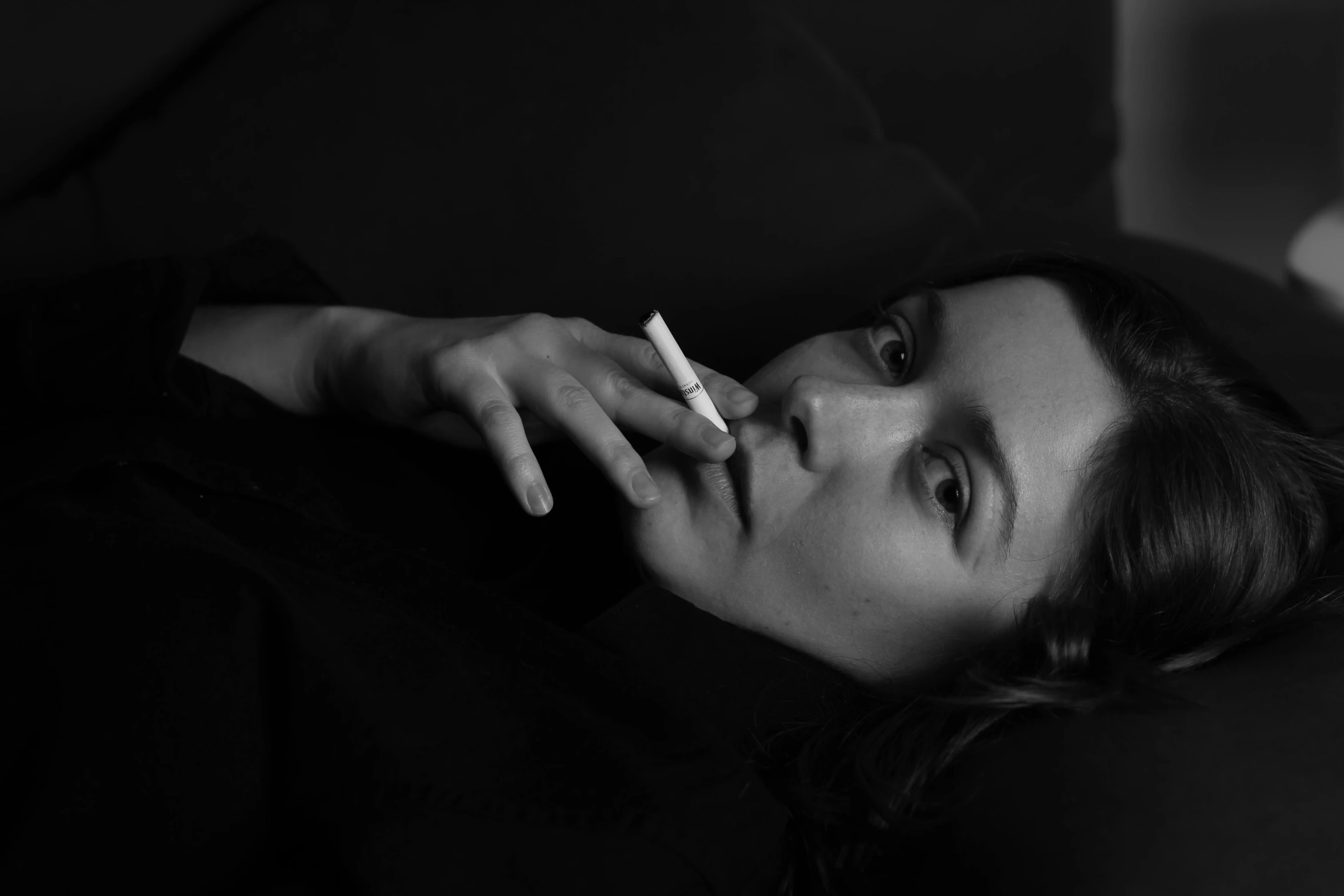 a woman laying on a couch with a cigarette in her mouth, by Emma Andijewska, angela sarafyan, portait image