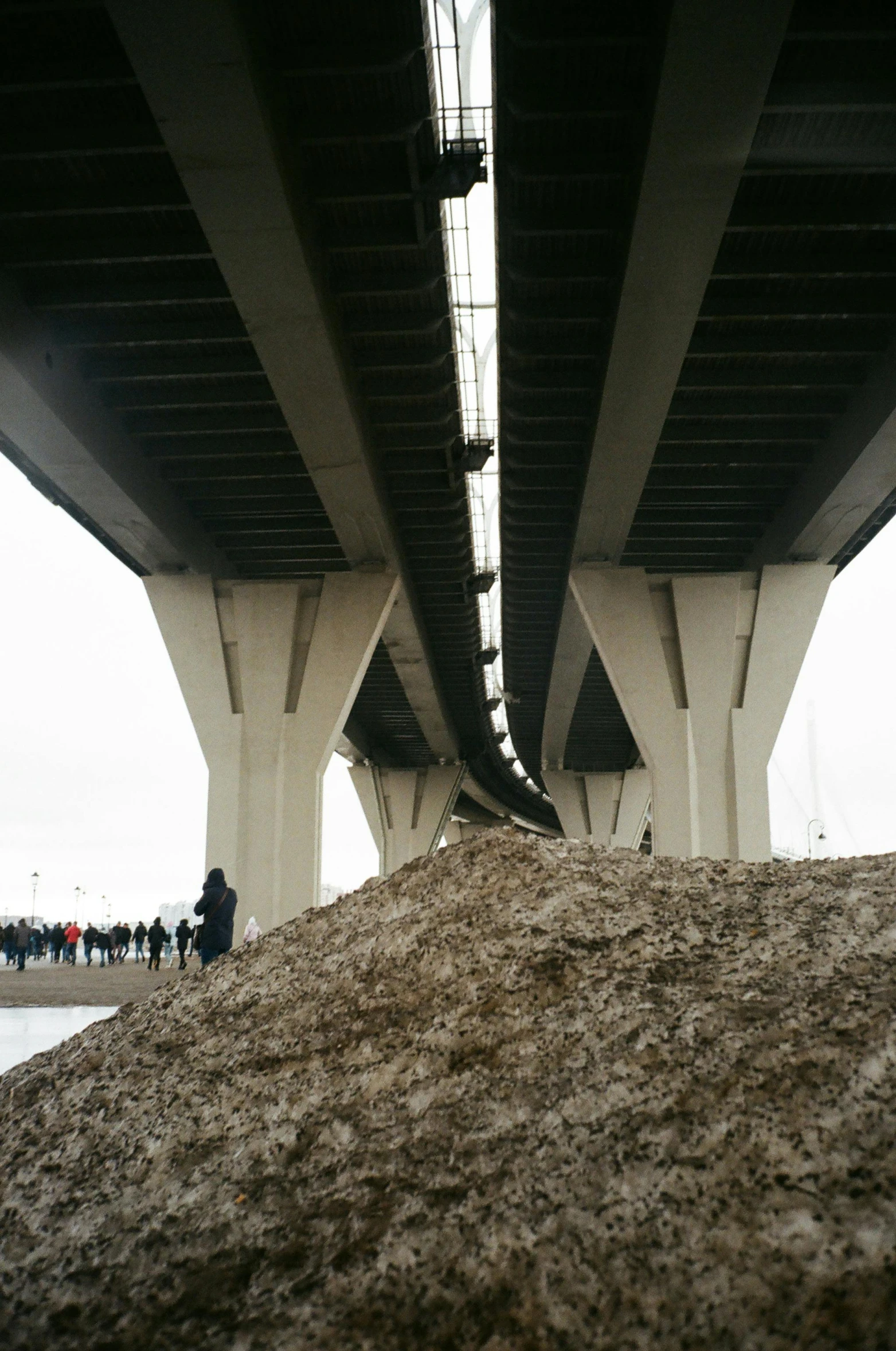 a large pile of sand under a bridge, an album cover, unsplash, helsinki, multiple stories, high snow, hziulquoigmnzhah