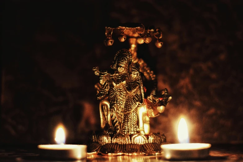 a statue sitting on top of a table next to two candles, a statue, pexels contest winner, visual art, gold madhubani, low key light, deity), brown