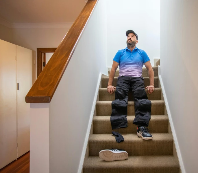 a man sitting on top of a set of stairs, wearing epic bionic implants, carpeted floor, manly, h3h3