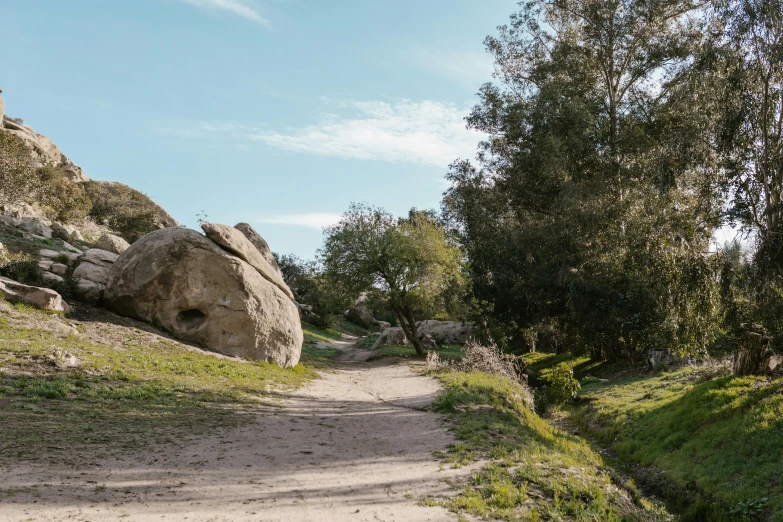 a man riding a skateboard down a dirt road, les nabis, large stones, park on a bright sunny day, landscape photo-imagery, malibu canyon