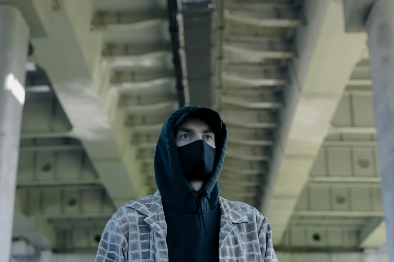 a man wearing a mask standing in a building, pexels contest winner, pewdiepie selfie at a bridge, hooded figure, neo noir, mrbeast