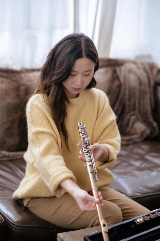 a woman sitting on a couch playing a flute, inspired by Gu Kaizhi, trending on pexels, ✨🕌🌙, sweat, casually dressed, iu