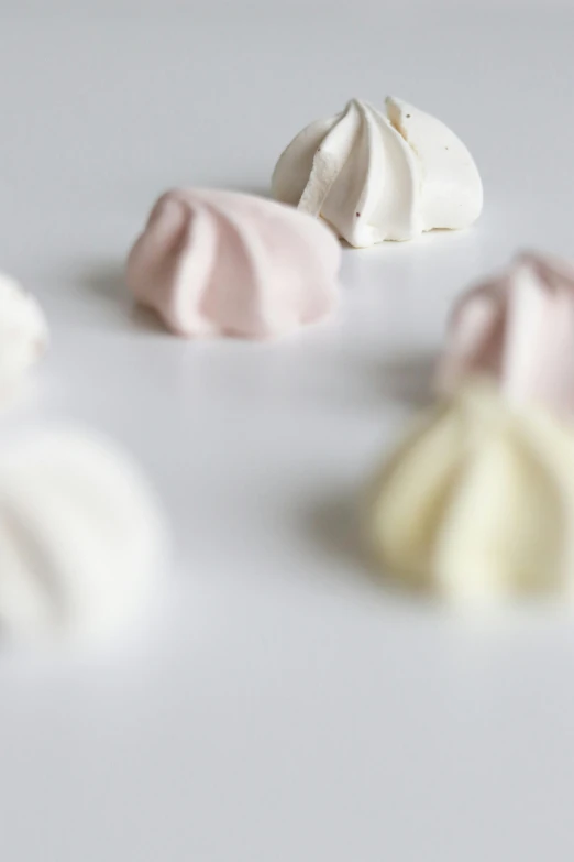 a group of white and pink meringue on a white surface, a picture, by Ruth Simpson, unsplash, made of glazed, high quality product, 3 colours, skyline