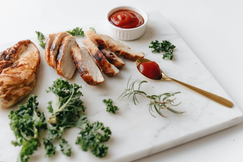 a white cutting board topped with meat and vegetables, ketchup, detailed product image, chicken, kailee mandel