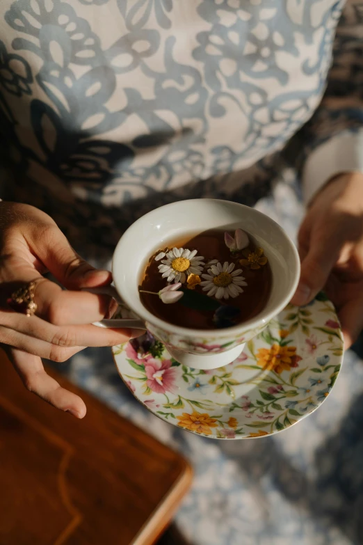 a close up of a person holding a cup of tea, floral clothes, botanicals, soup, slide show