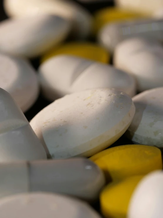 a pile of white and yellow pills sitting on top of each other, by Greg Rutkowski, unsplash, multiple stories, closeup photo, 15081959 21121991 01012000 4k