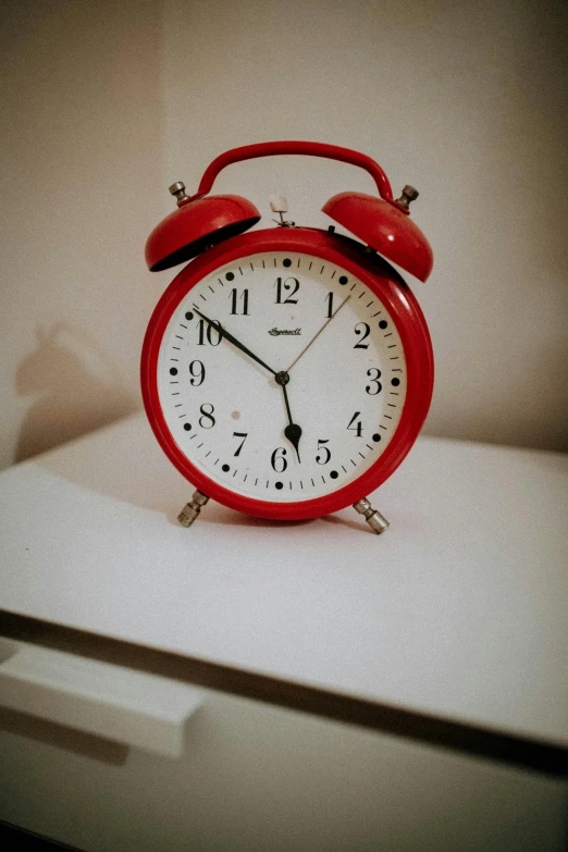 a red alarm clock sitting on top of a white counter, photograph taken in 2 0 2 0, classic art, lights on, bells