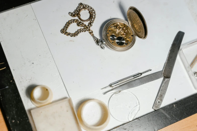 a clock sitting on top of a table next to a pair of scissors, an etching, unsplash, assemblage, bone jewellery, marble and gold, small manufacture, thumbnail
