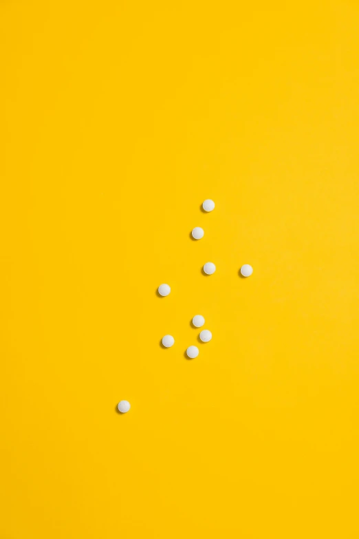 pills scattered on a yellow background, by Winona Nelson, antipodeans, professional product photography, white in color, reverse, magnesium