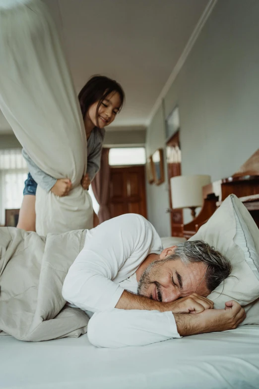 a man laying on top of a bed next to a woman, a stock photo, pexels contest winner, happening, daughter, grey, dad energy, hide the pain harold