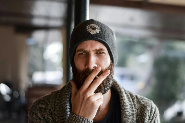 a man with a beard smoking a cigarette, wearing a beanie, ben watts, avatar image, environmental shot