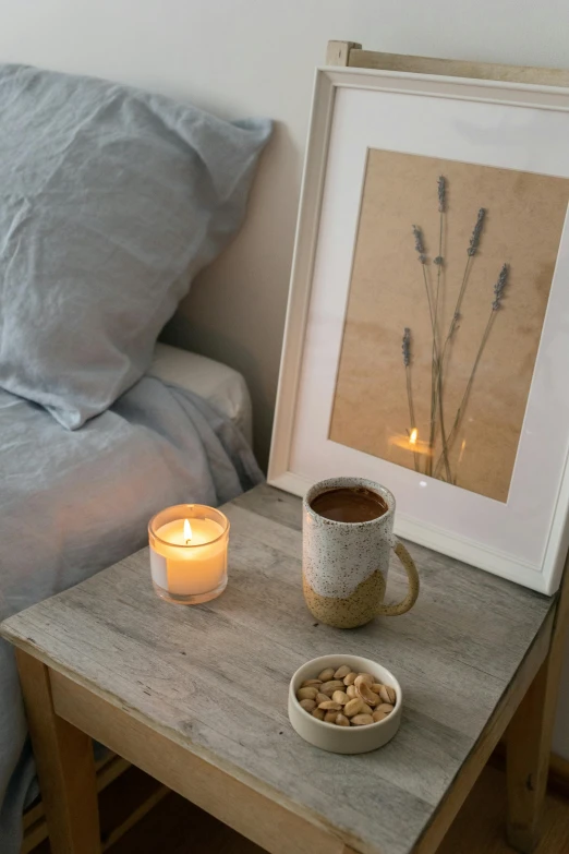 a table topped with a bowl of cereal next to a lit candle, a charcoal drawing, visual art, serene bedroom setting, with a cup of hot chocolate, framed in image, home display
