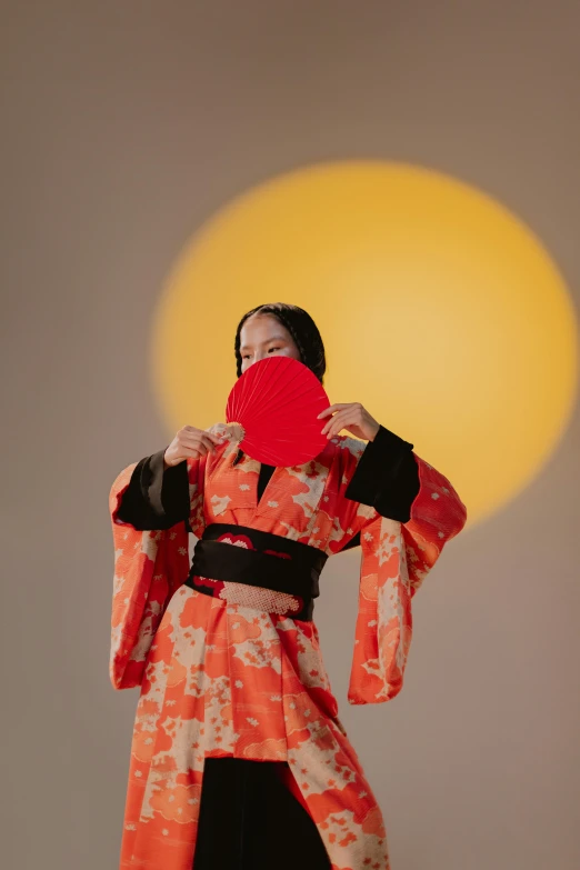 a woman in a kimono holding a red fan, an album cover, unsplash, with full moon in the sky, orange sun set, hood and shadows covering face, bella poarch