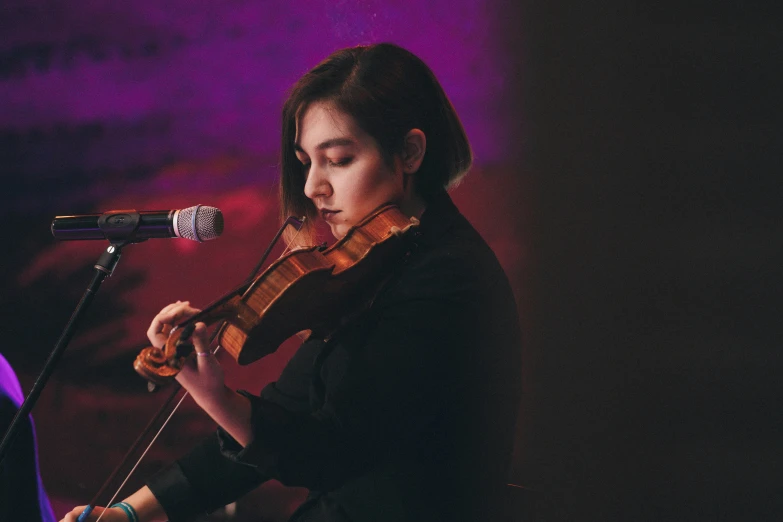 a woman playing a violin in front of a microphone, pexels contest winner, antipodeans, charli bowater and artgeem, avatar image, maisie williams, live performance