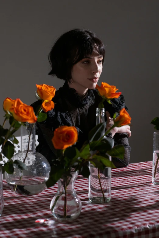 a woman sitting at a table with flowers in vases, an album cover, inspired by Winona Nelson, krysten ritter, detail shot, rose-brambles, dezeen