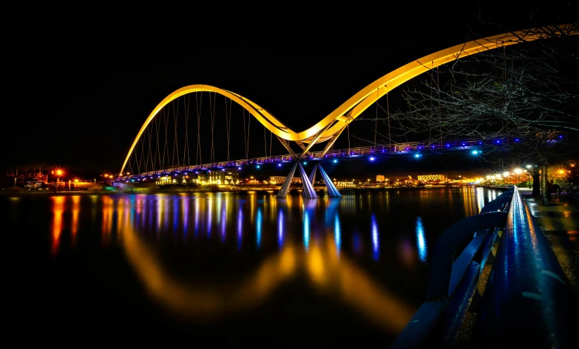a bridge over a body of water at night, pexels contest winner, golden curve structure, iowa, reflection lumen mapping, blue and orange rim lights