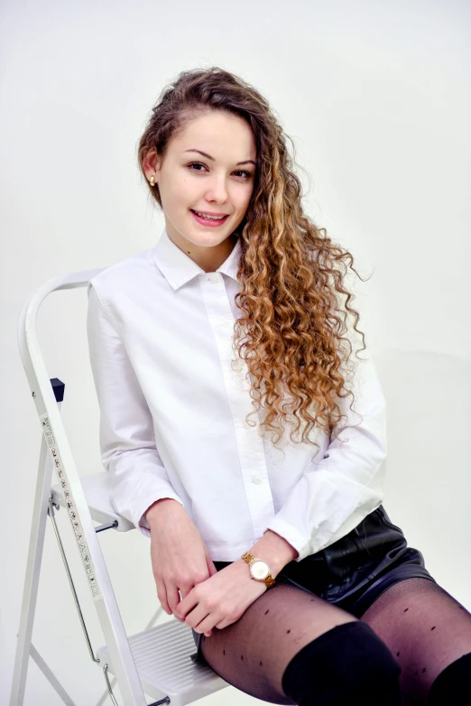 a woman sitting on top of a white chair, fair curly hair, russian academic, wearing a shirt, teen