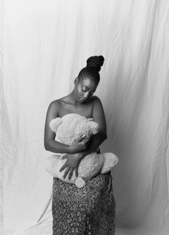 a black and white photo of a woman holding a teddy bear, inspired by Carrie Mae Weems, adut akech, ( ( photograph ) ), shot in the photo studio, with tears