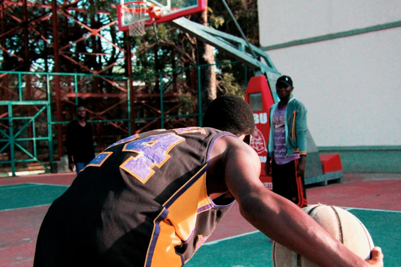 a man holding a basketball on top of a basketball court, on ground, back view. nuri iyem, documentary still, dunking