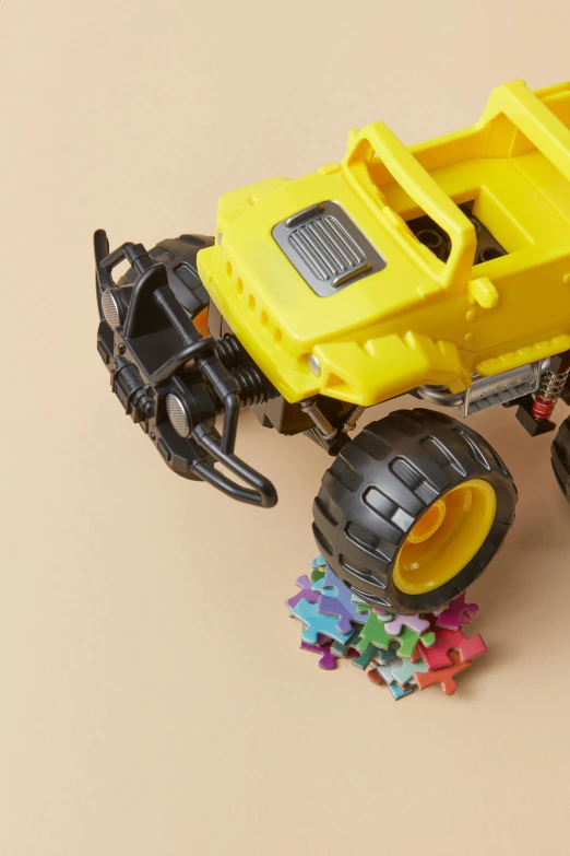 a yellow toy truck sitting on top of a pile of confetti, a jigsaw puzzle, off-roading, neck zoomed in, zoomed in, spiky