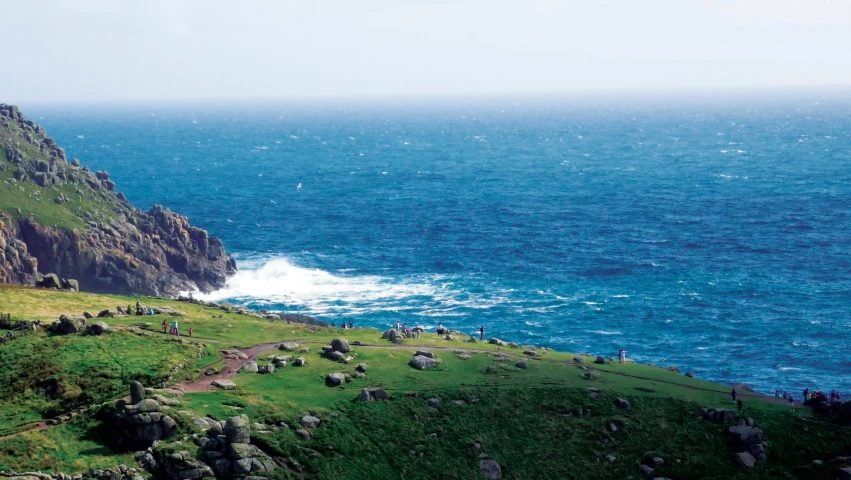 a group of people standing on top of a lush green hillside next to the ocean, shepherd's crook, offshore winds, piroca, advert