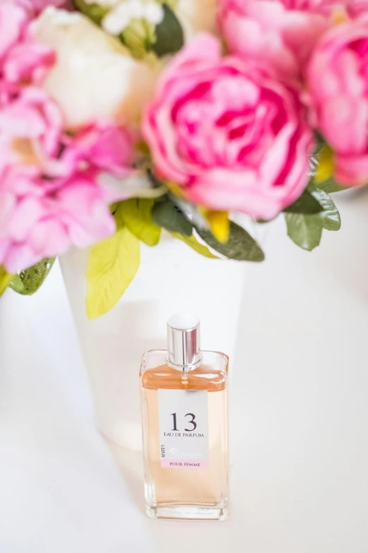 a bottle of perfume sitting next to a vase of flowers, countdown, 1 3 3 4 building, on a white table, thumbnail