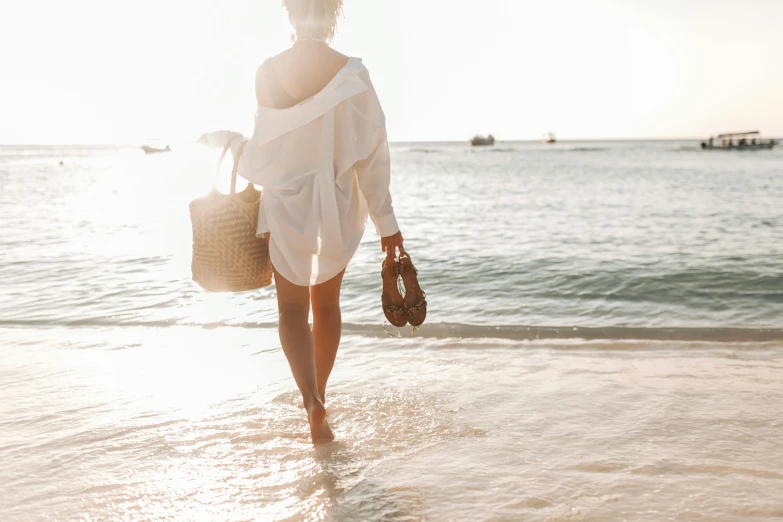 a woman walking on the beach carrying a basket, pexels contest winner, wearing a white button up shirt, bare legs, heat shimmering, deep tan skin