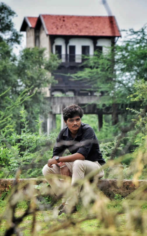 a man sitting on a log in front of a house, by Rajesh Soni, around 20 yo, portait photo profile picture, avatar image, tourist photo