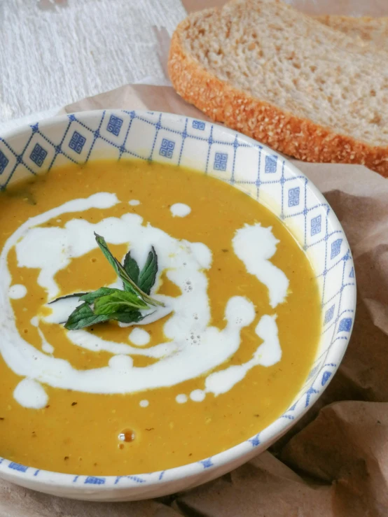 a bowl of soup next to a slice of bread, trending on unsplash, pumpkin, high quality product image”, background image, herbs