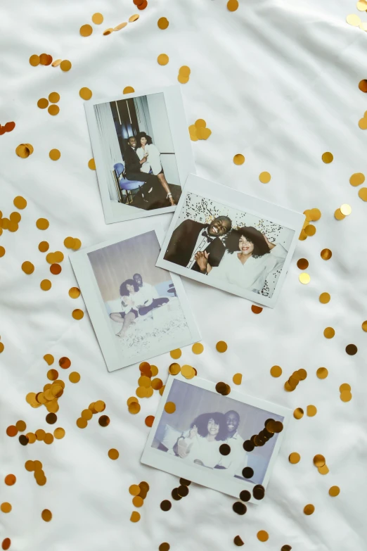 a bunch of pictures sitting on top of a bed covered in confetti, a polaroid photo, inspired by Elsa Bleda, pexels contest winner, white and gold color scheme, sza, 1 9 7 0 s style, 8 k photo