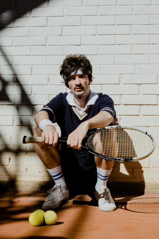 a man sitting on the ground with a tennis racket, classic vibes, press shot, ethan klein, waist up portrait