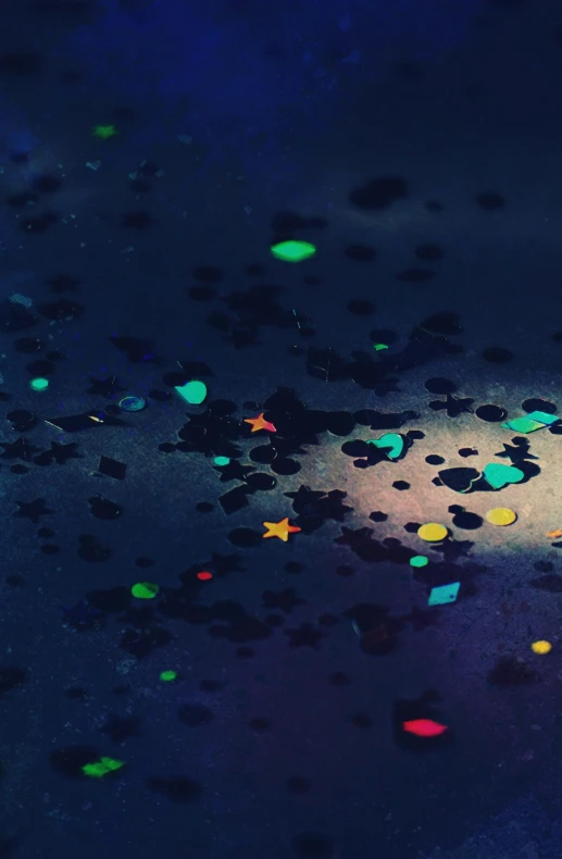 a close up of confetti sprinkles on a wet surface, inspired by Filip Hodas, space art, some fireflies, ilustration, chillhop, grainy movie still