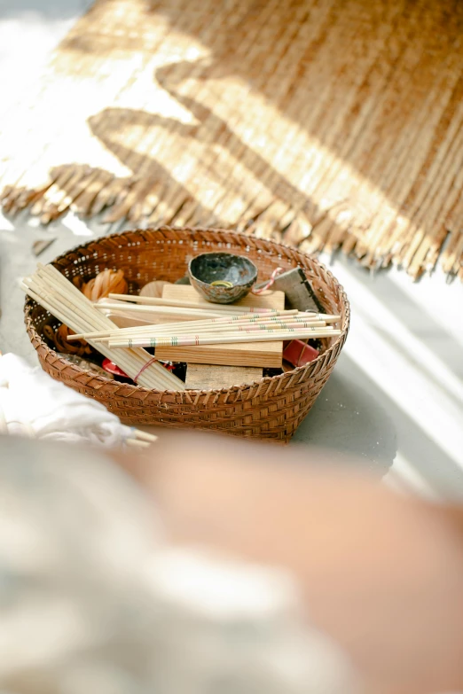 a basket filled with sticks sitting on top of a table, a picture, unsplash, incense, sunny atmosphere, with small object details, product shot