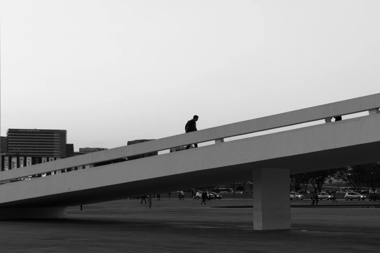 a black and white photo of a person on a bridge, inspired by Ned M. Seidler, pexels contest winner, brutalism, people on the ground, oscar niemeyer, white pale concrete city, no people 4k