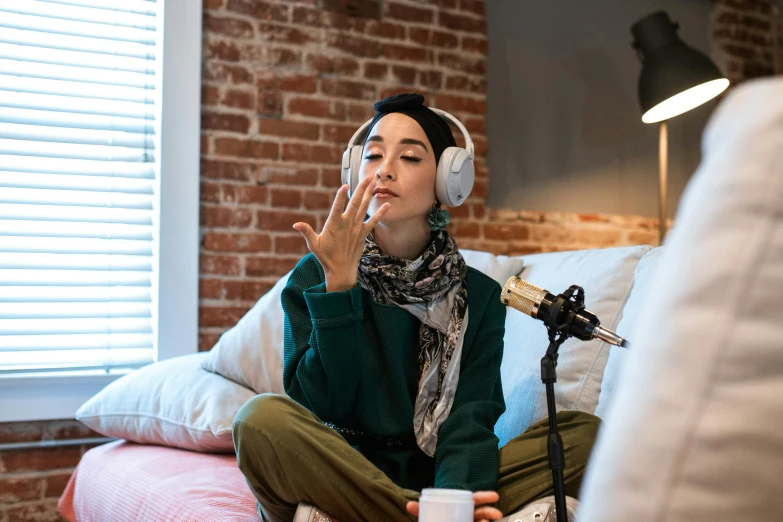 a woman sitting on a bed with headphones on, trending on pexels, hurufiyya, middle finger, white hijab, sitting in a lounge, h3h3