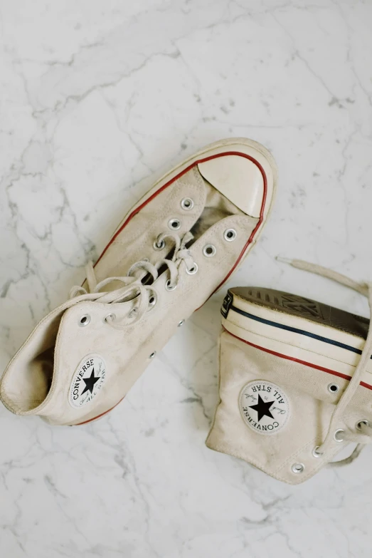 a pair of shoes sitting on top of a marble floor, trending on pexels, converse, cream and white color scheme, late 1 9 6 0's, battered