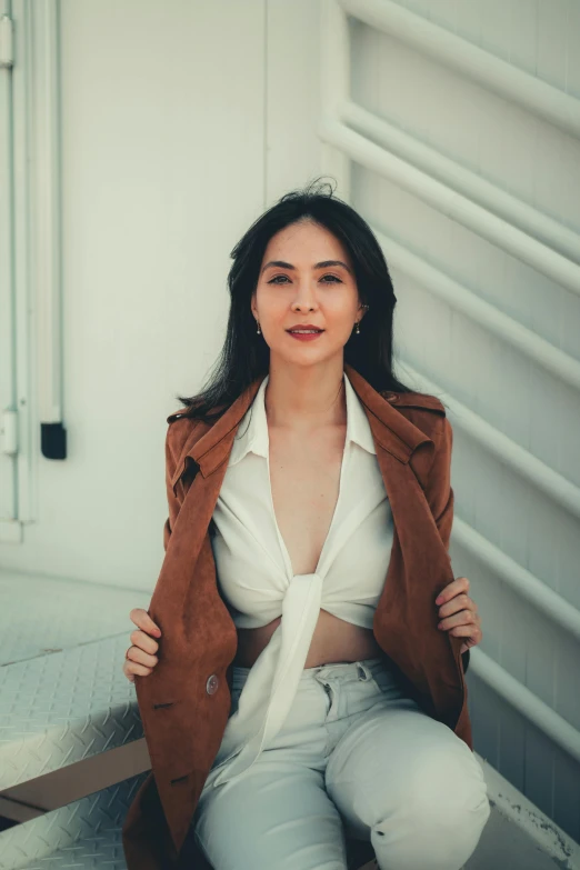 a woman sitting on the steps of a building, inspired by helen huang, pexels contest winner, happening, cropped shirt with jacket, attractive face and body, on a white table, brown jacket