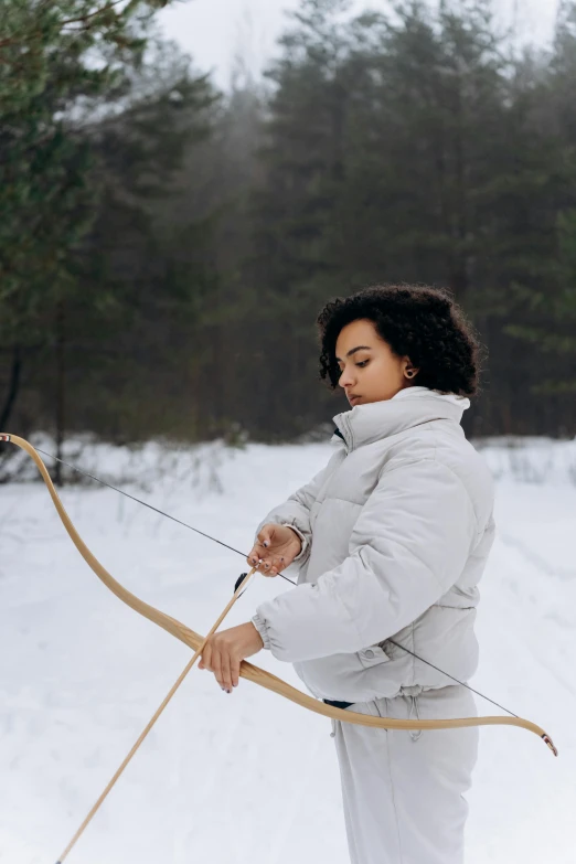 a woman holding a bow and arrow in the snow, pexels contest winner, imaan hammam, puffer jacket, marina abramovic, gif