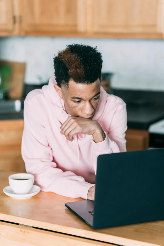 a man sitting at a kitchen table with a laptop, by Cosmo Alexander, trending on pexels, sitting on a mocha-colored table, ashteroth, looking serious, pink hue