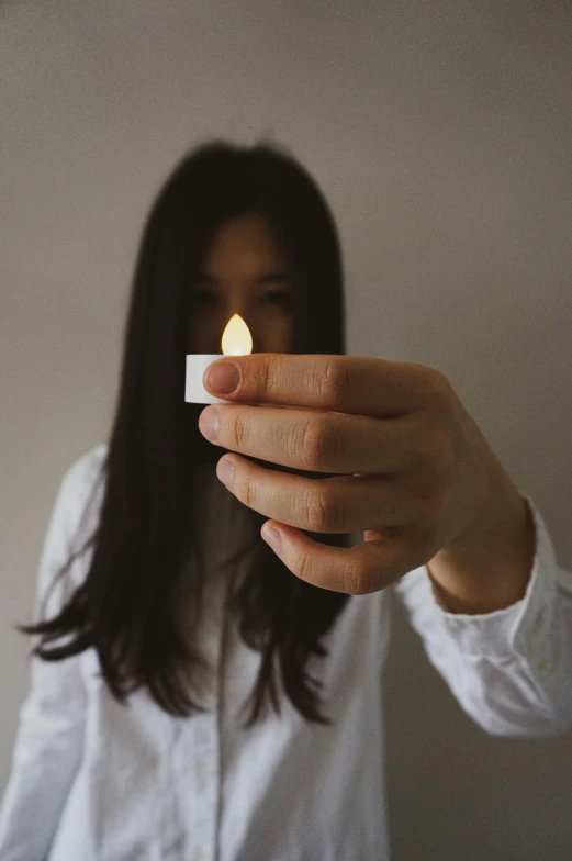 a woman holding a lit candle in front of her face, pexels contest winner, minimalism, chinese girl, medium format. soft light, tiny firespitter, instagram post