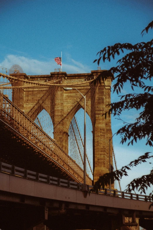 a very tall bridge with a flag on top of it, inspired by Elsa Bleda, pexels contest winner, brooklyn, zoomed in, 1999 photograph, brown