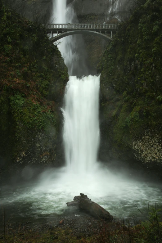 a waterfall with a bridge in the background, oregon, wide nostrils, very wet, incredibly ethereal